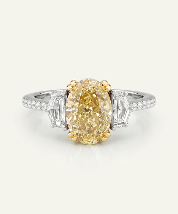 Diamond ring with a yellow diamond and baguette cut side stones on a white background