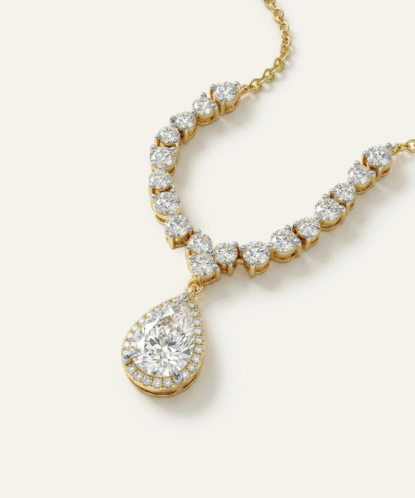 Gold necklace with a large teardrop-shaped diamond pendant on a white background
