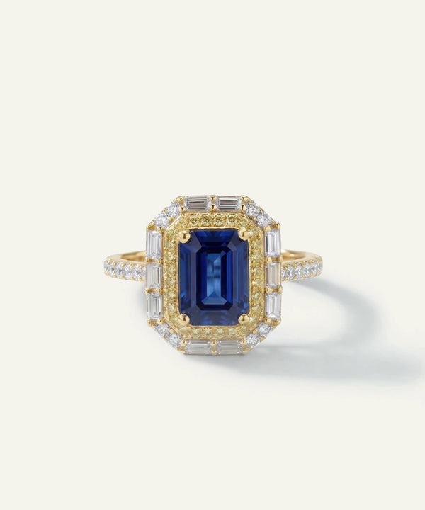 Gold ring with a blue gemstone and diamond accents on a white background