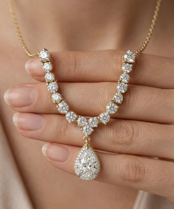 Diamond necklace held by a hand against a neutral background