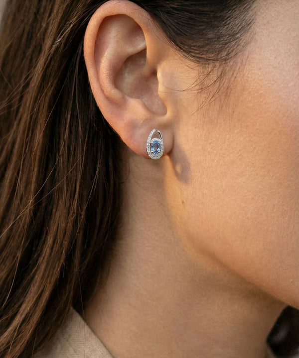 Close-up of an ear wearing a diamond earring with a blurred background