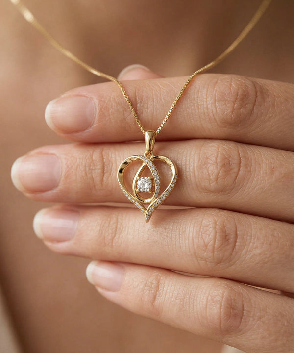 Gold heart-shaped pendant with a diamond held between fingers against a neutral background