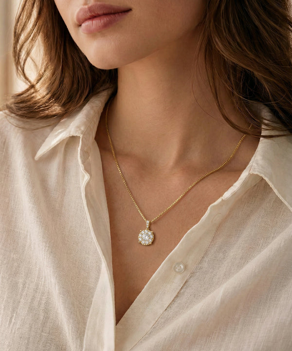 Close-up of a person wearing a gold necklace with a pendant, set against a neutral background.