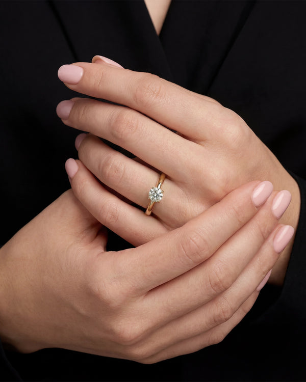 Close-up of a hand wearing a diamond ring with a black background
