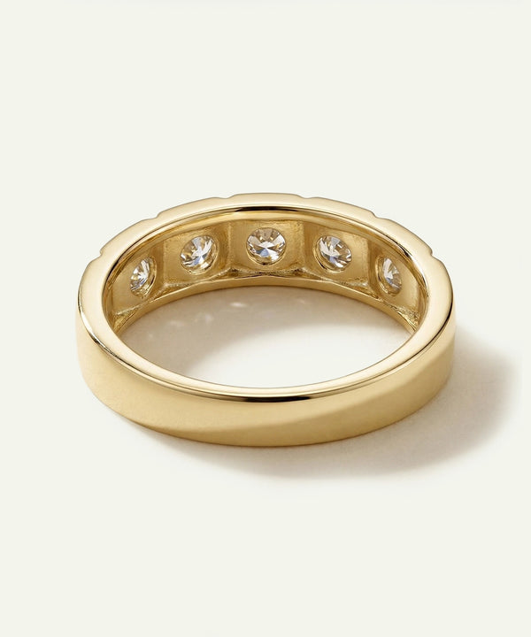 Gold ring with embedded diamonds on a light beige background