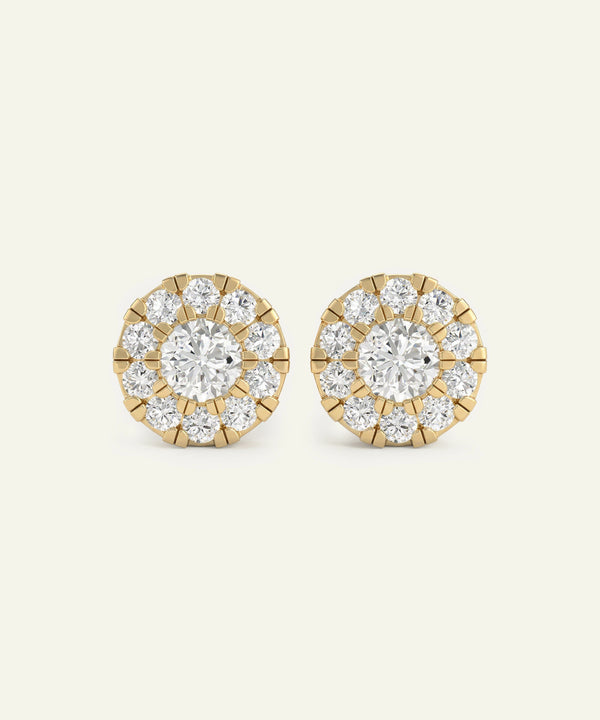 Pair of gold and diamond stud earrings on a light beige background
