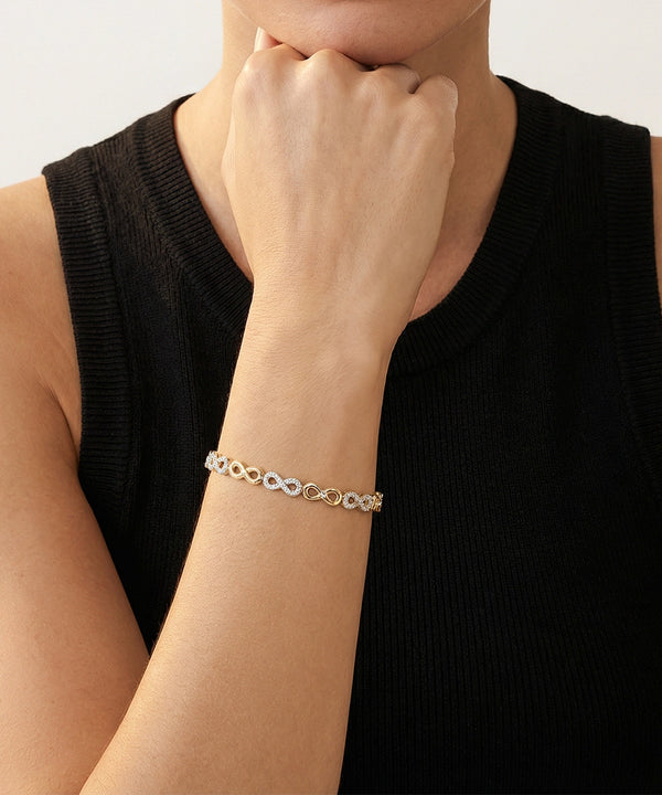 Person wearing a silver bracelet on a plain background