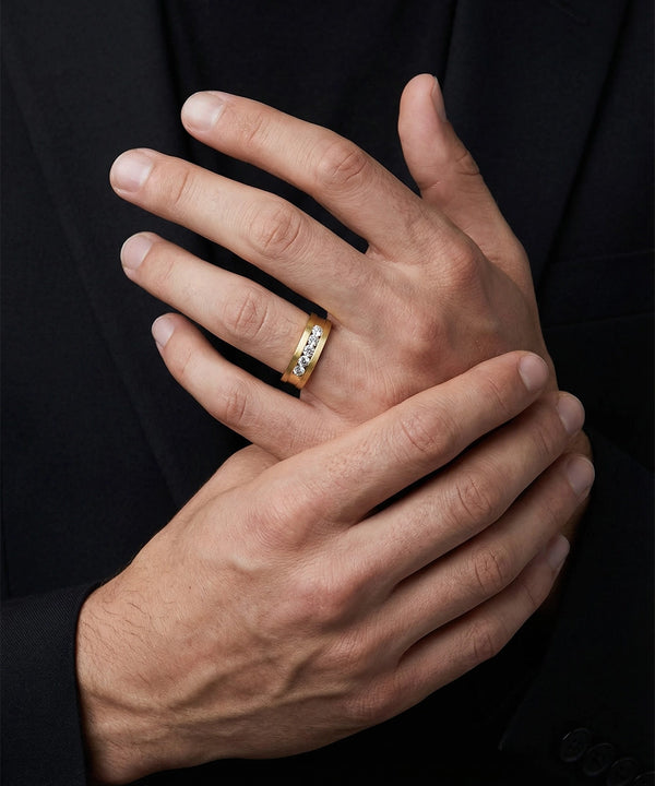 Close-up of a hand wearing a gold ring with a diamond on a black background