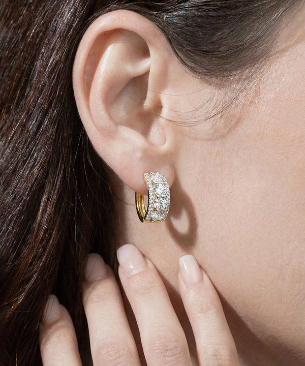 Close-up of a person wearing a diamond hoop earring.