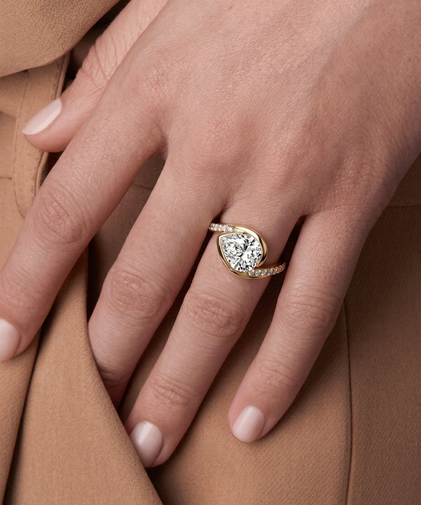Close-up of a hand wearing a diamond ring on a brown fabric background