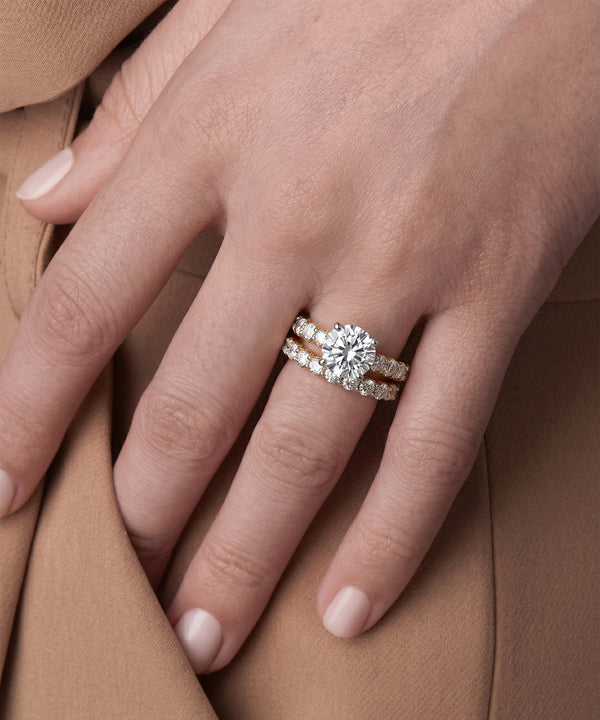 Close-up of a hand wearing a diamond ring on a brown fabric background