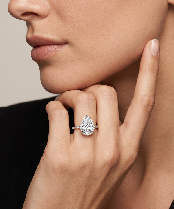 Close-up of a hand wearing a diamond ring with a neutral background