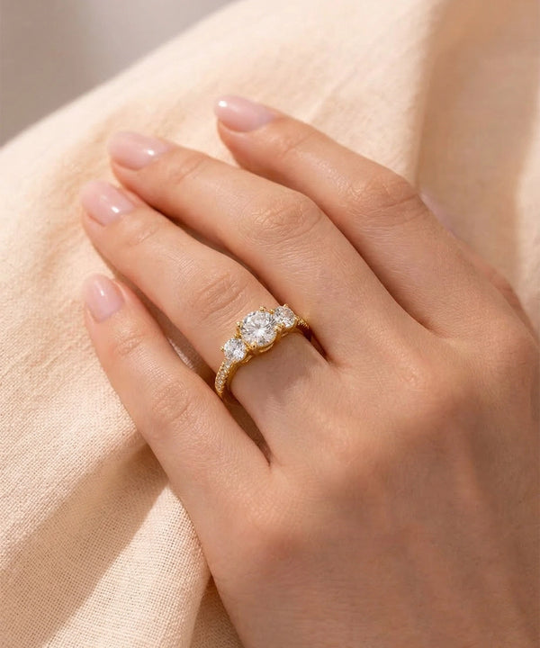 Rose gold ring with a diamond on a hand against a beige fabric background