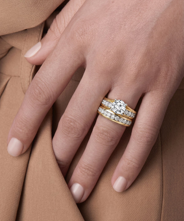 Close-up of a hand wearing two diamond rings on a brown fabric background
