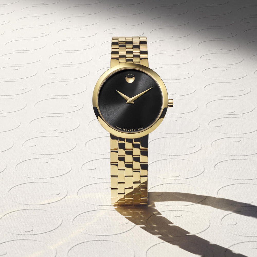 Gold wristwatch with black face on a textured white background