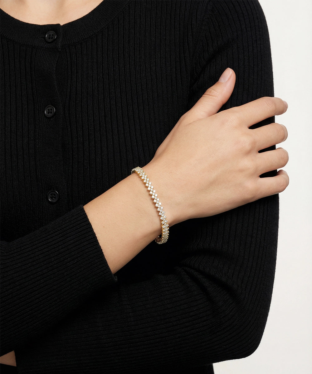 Person wearing a gold bracelet on a plain background