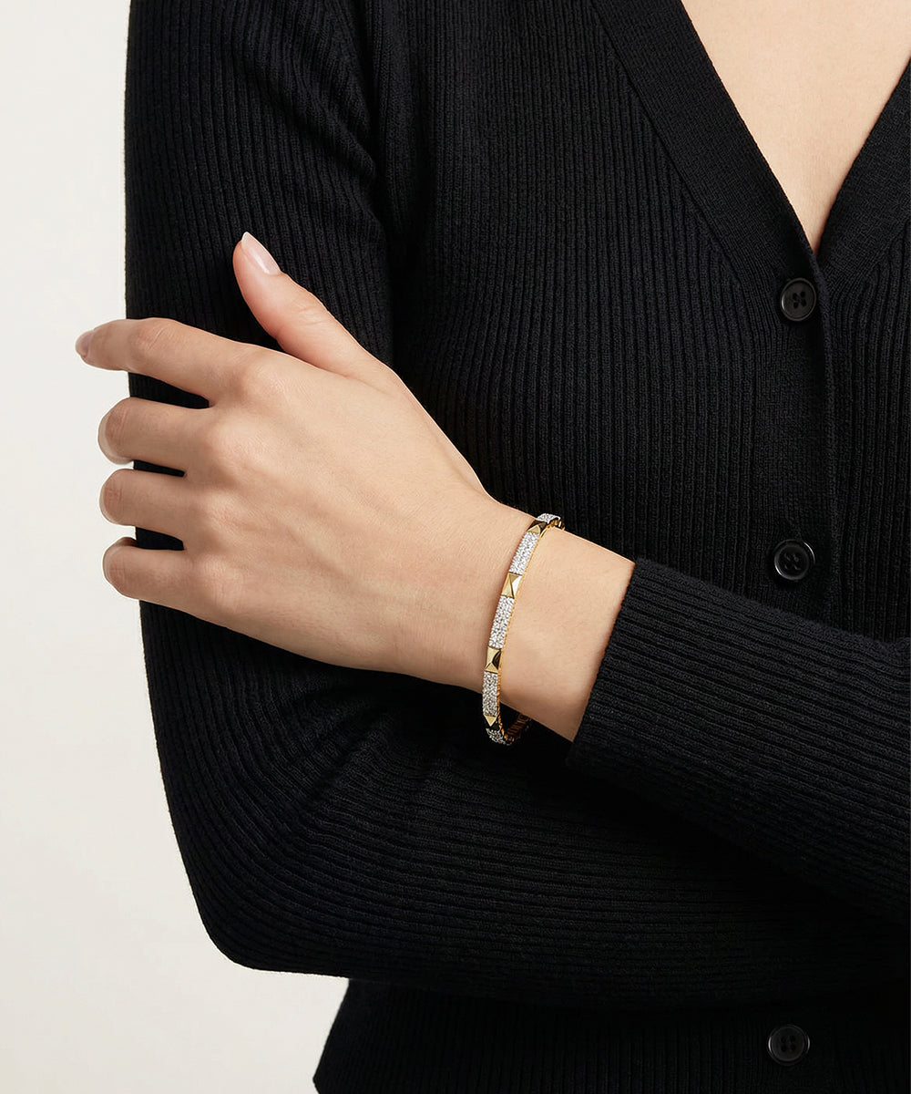 Person wearing a gold bracelet on a plain background