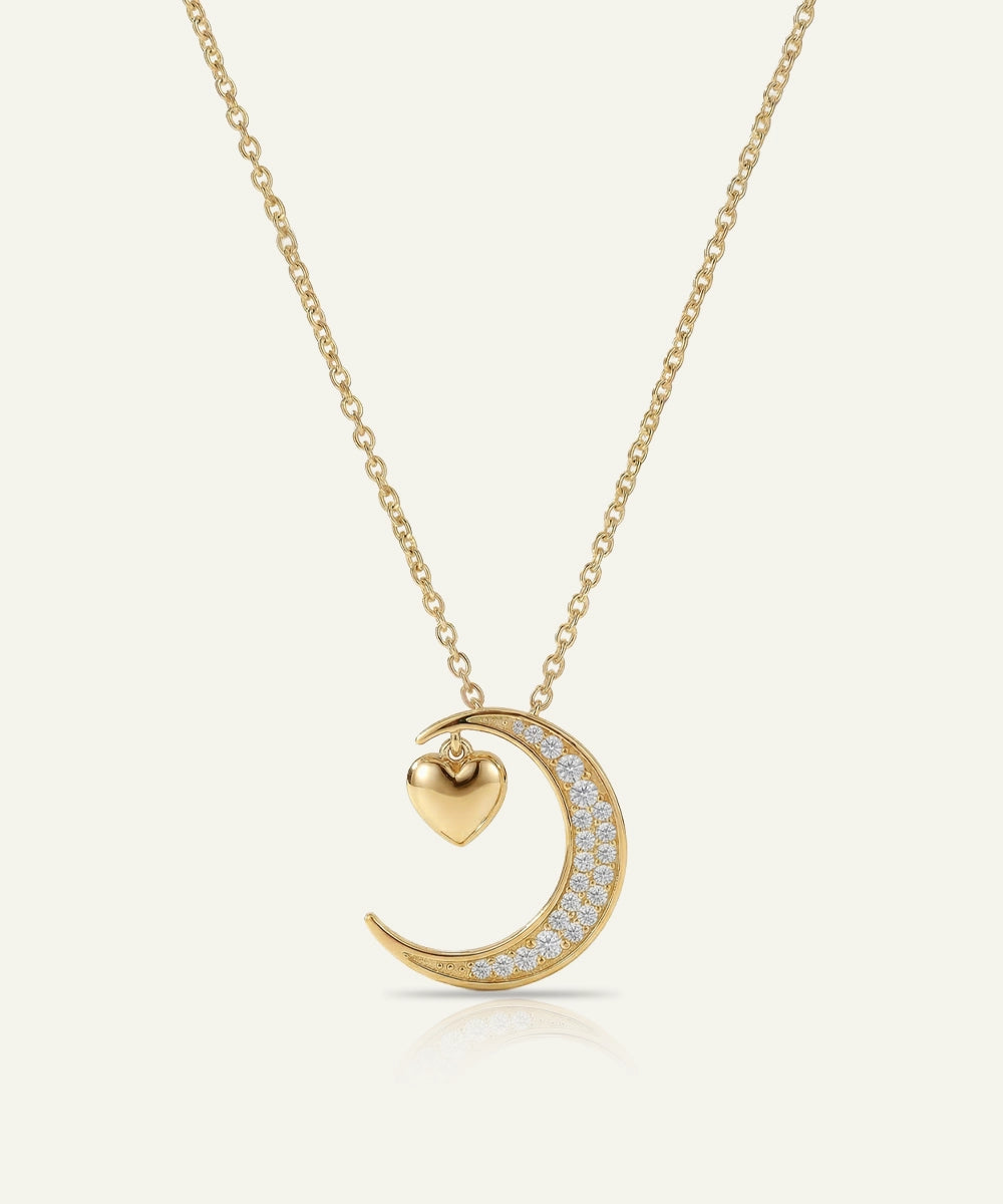 Gold necklace with a crescent moon and heart pendant on a white background