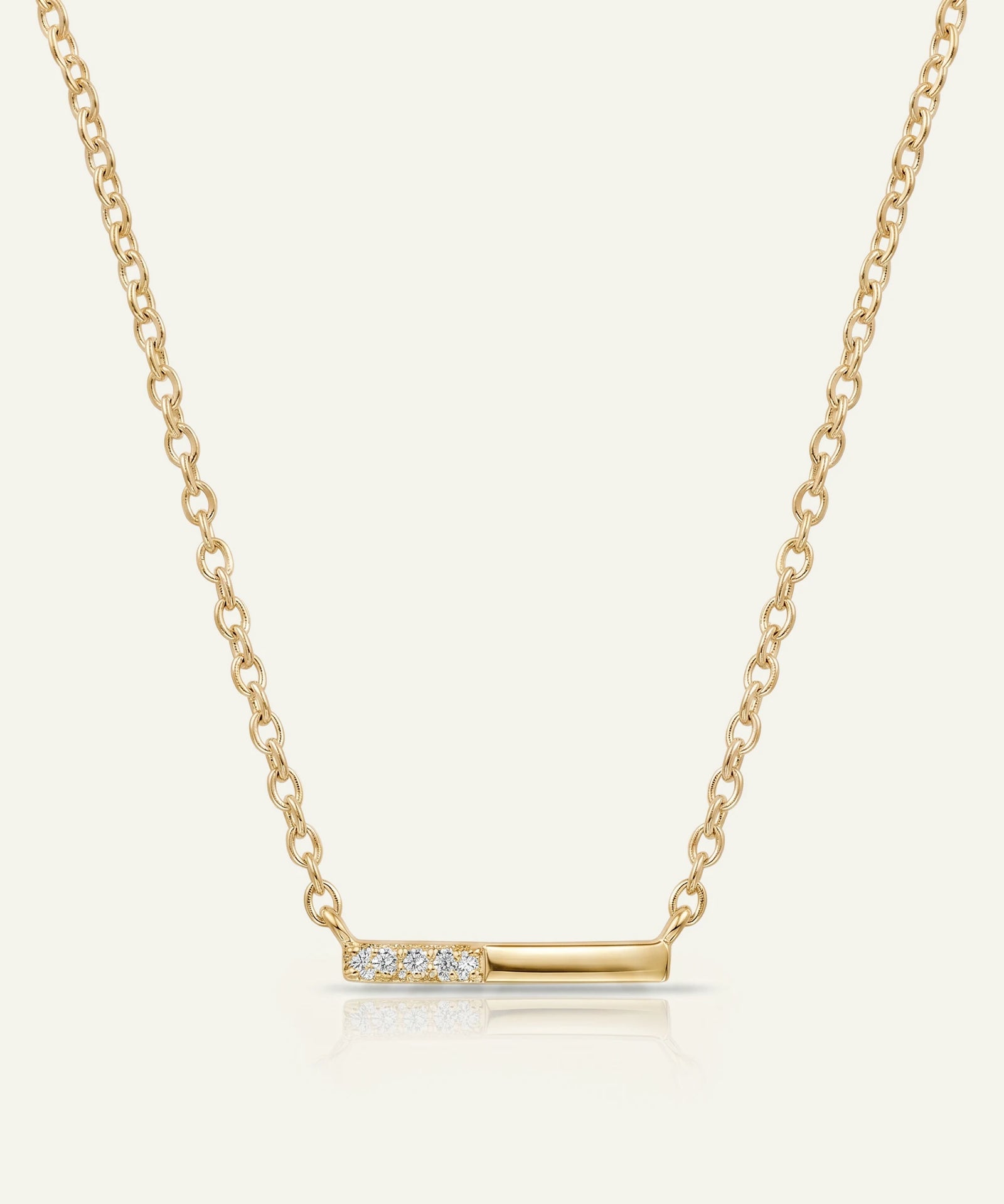 Gold necklace with a bar pendant on a light beige background