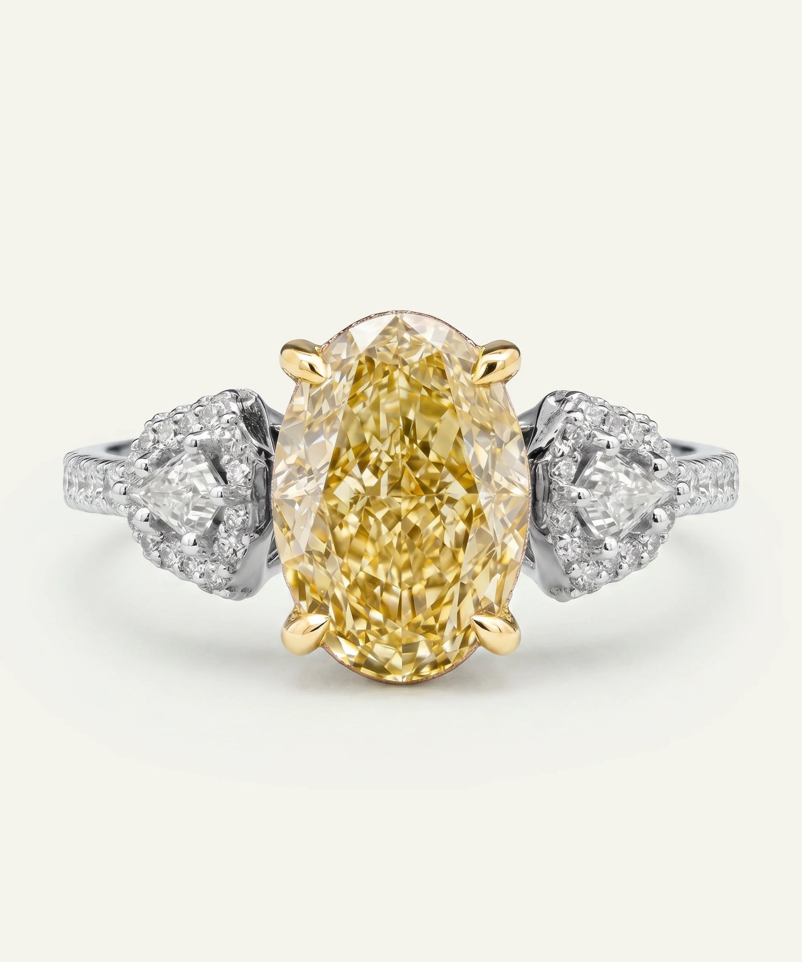 Gold ring with a yellow diamond and silver side stones on a white background