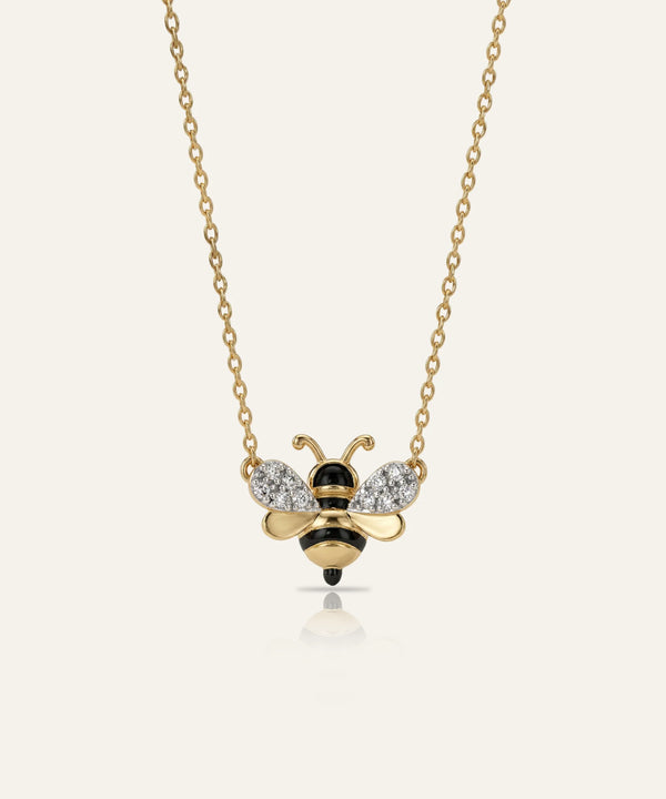 Gold bee-shaped necklace with diamond accents on a white background