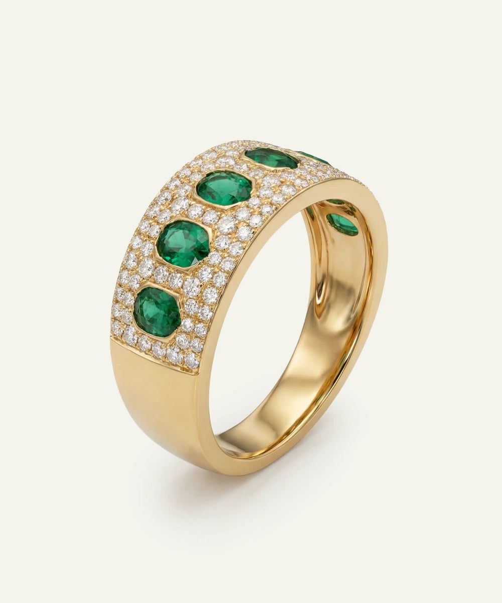 Gold ring with emeralds and diamonds on a white background