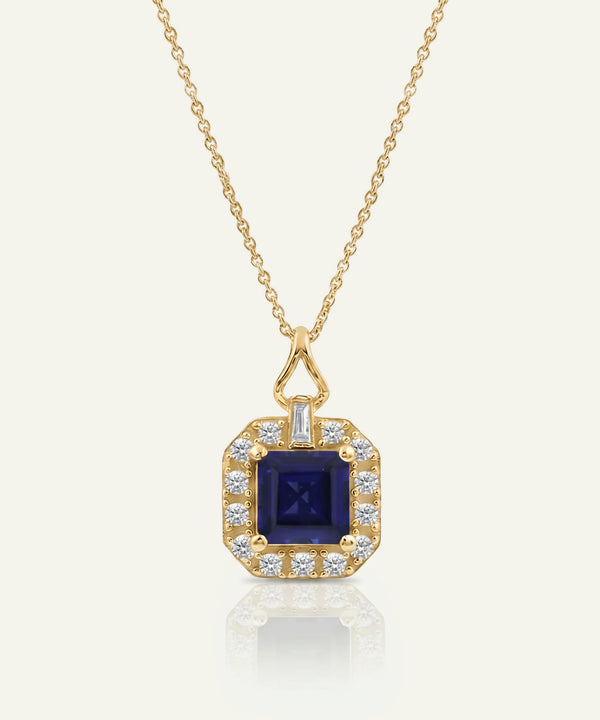 Yellow gold pendant necklace featuring a square-cut deep blue sapphire center stone framed by a halo of round brilliant diamonds, suspended from a delicate gold chain against a light neutral background.