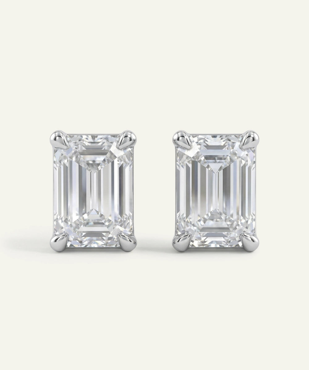 Pair of emerald-cut diamond stud earrings on a white background