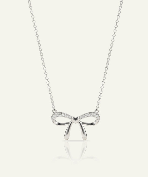 Silver bow-shaped pendant necklace on a white background