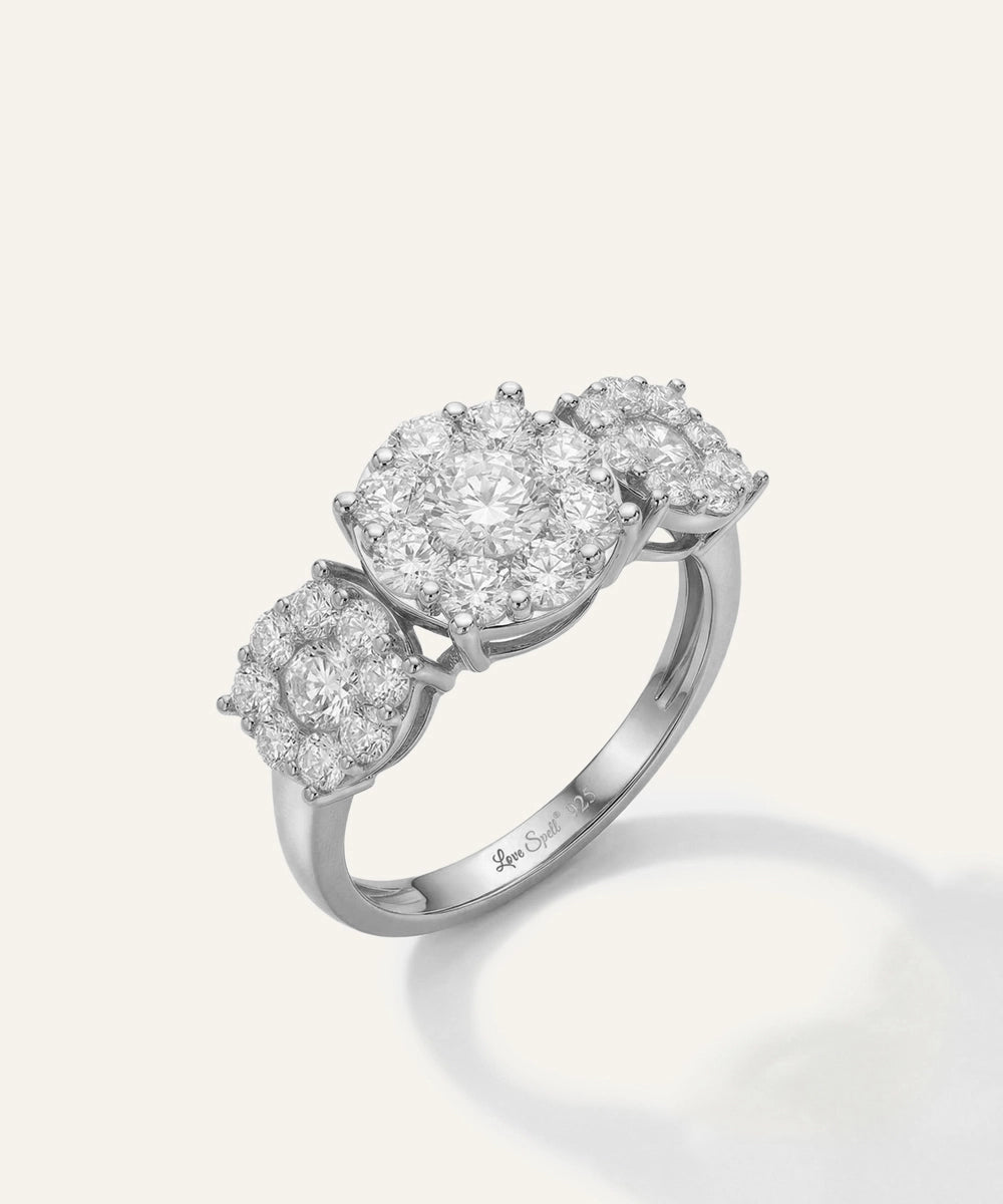 Diamond ring with three oval-shaped gemstones on a light gray background