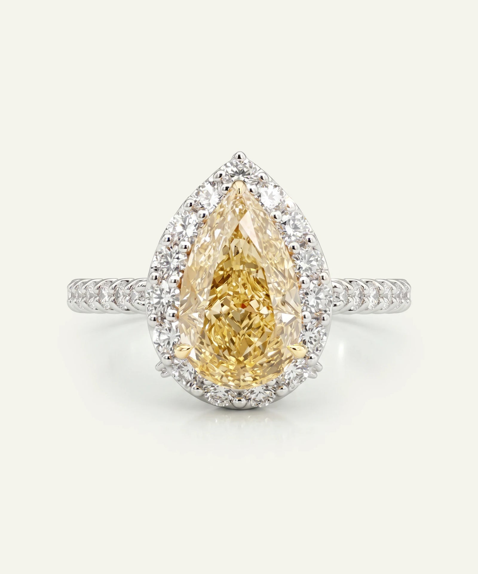 Teardrop-shaped yellow diamond ring with a white gold band on a light gray background