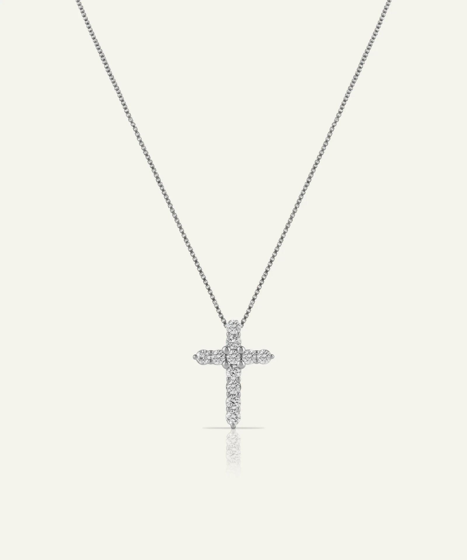 Silver cross necklace with diamonds on a light gray background