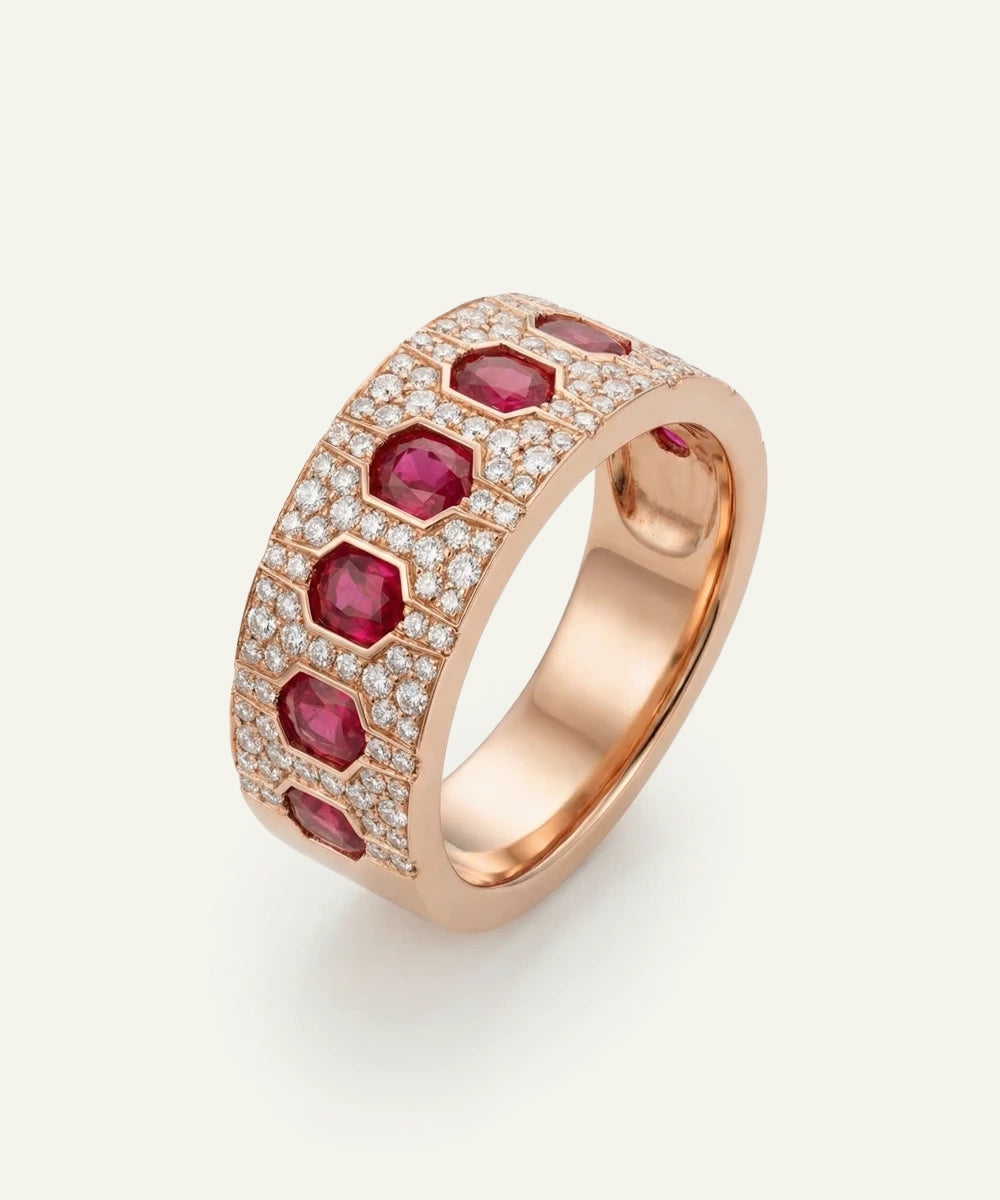 Rose gold ring with red gemstones and small diamonds on a light gray background