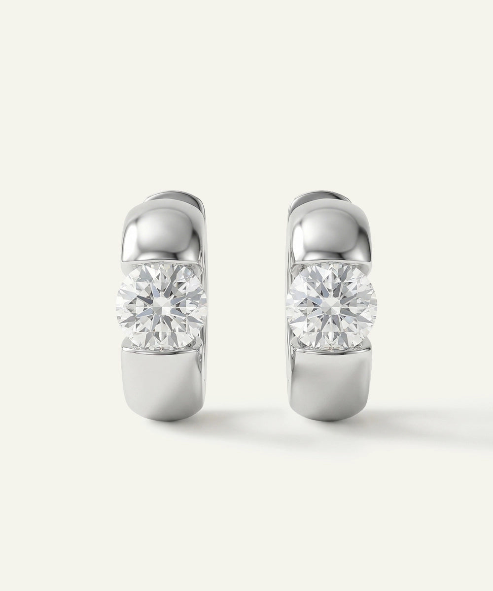 Pair of silver hoop earrings with clear gemstones on a white background