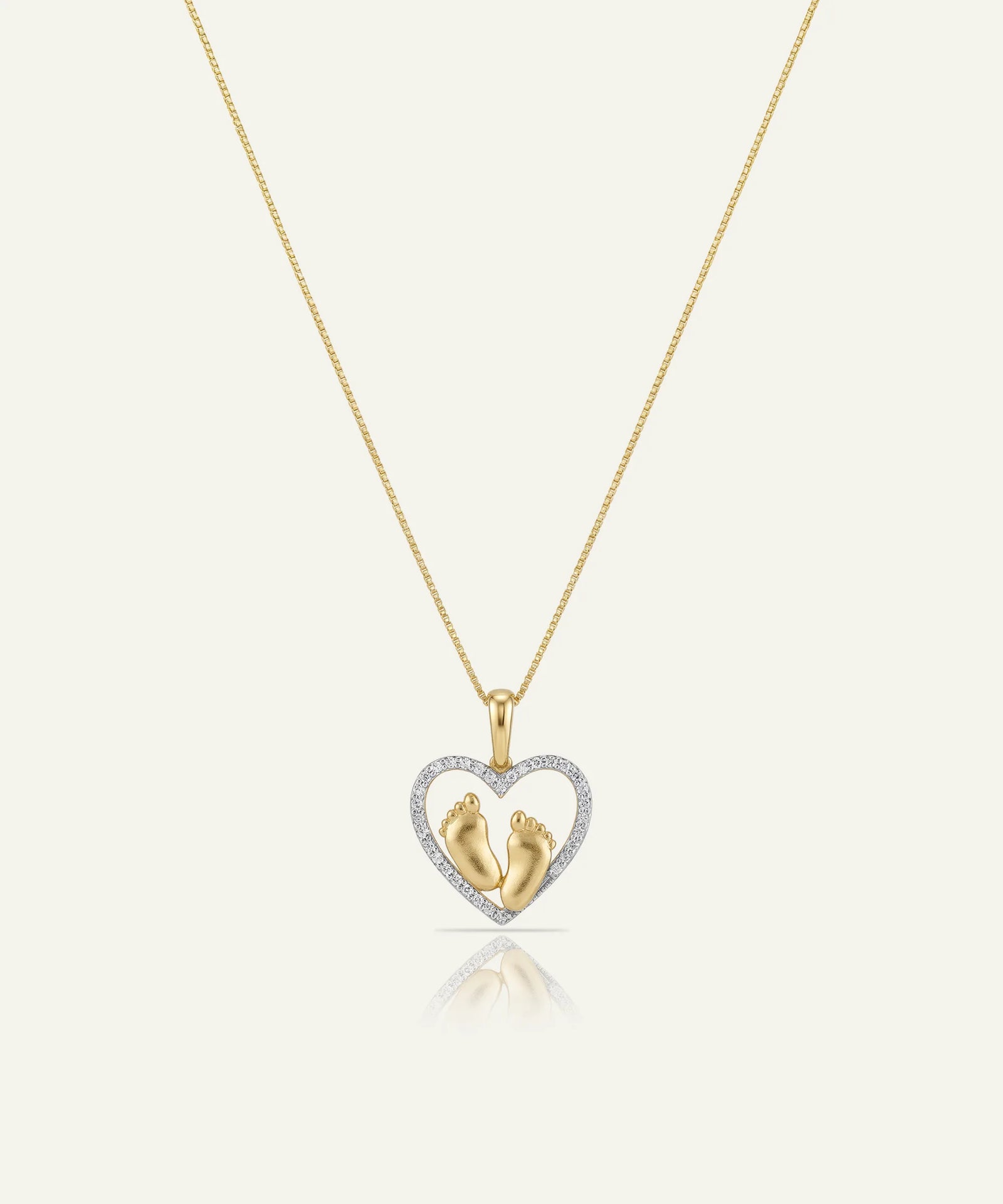 Gold necklace with a heart-shaped pendant featuring two small figures, on a white background.