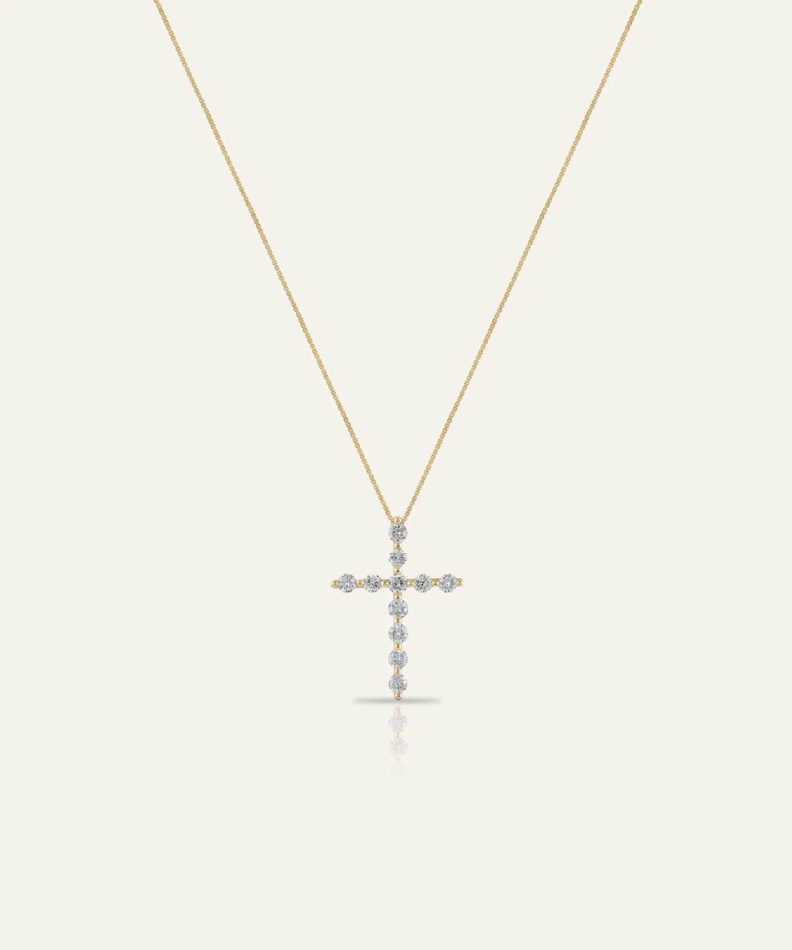 Gold cross necklace with small stones on a white background