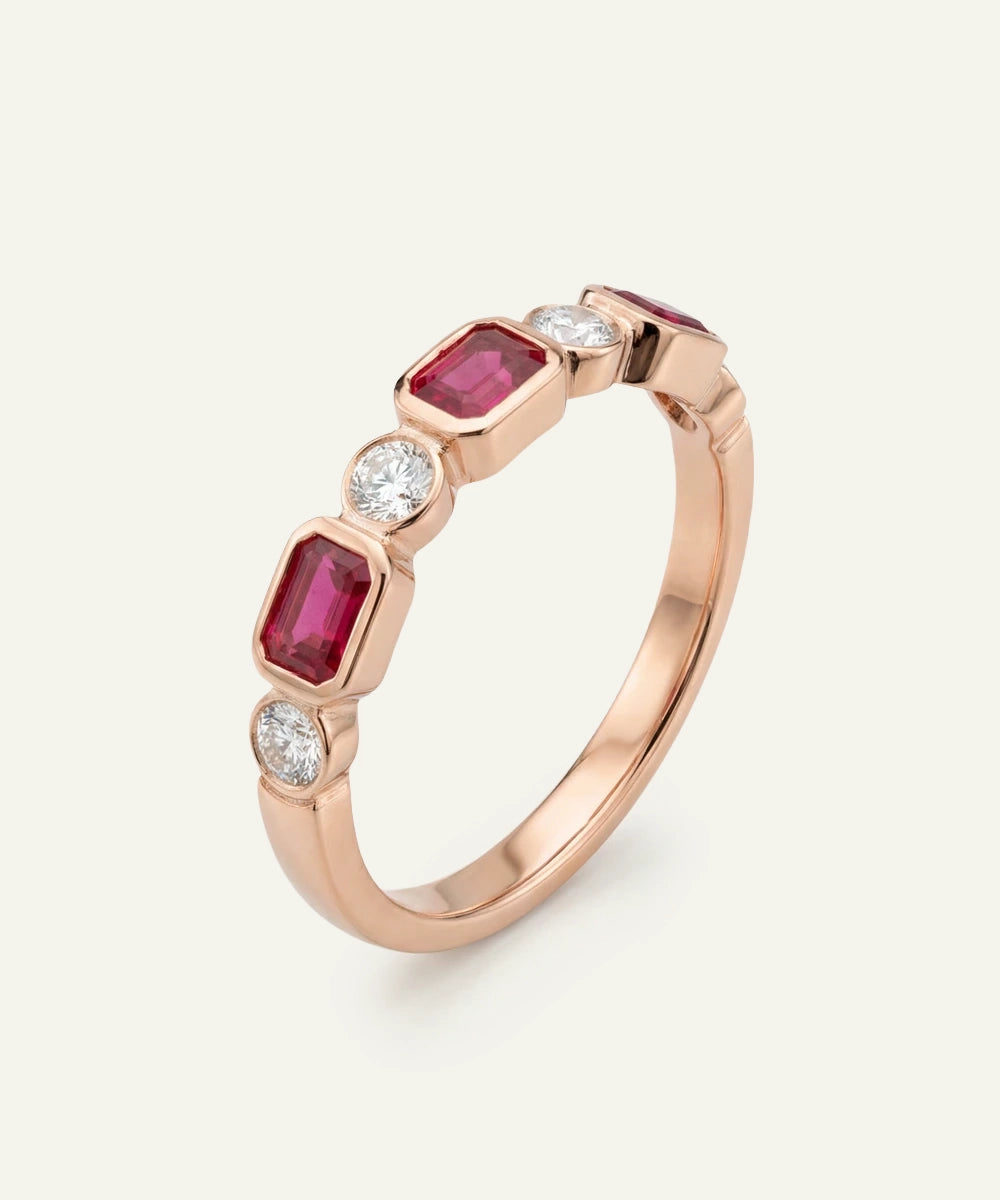 Rose gold ring with red gemstones and diamonds on a white background