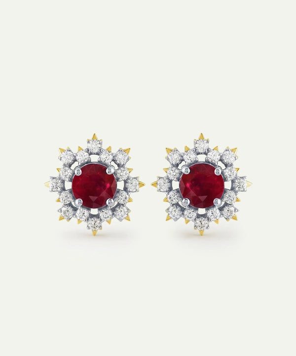 Pair of earrings with red gemstones and diamond-studded halo on a white background