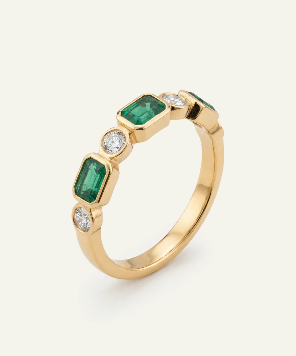 Gold ring with emeralds and diamonds on a white background