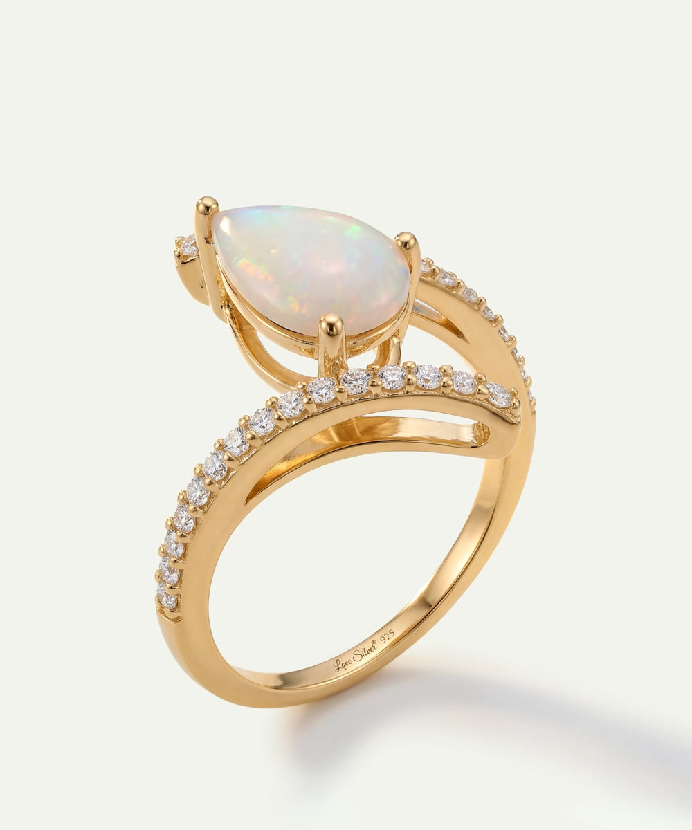 Gold ring with a pear-shaped opal stone and diamond accents on a light background