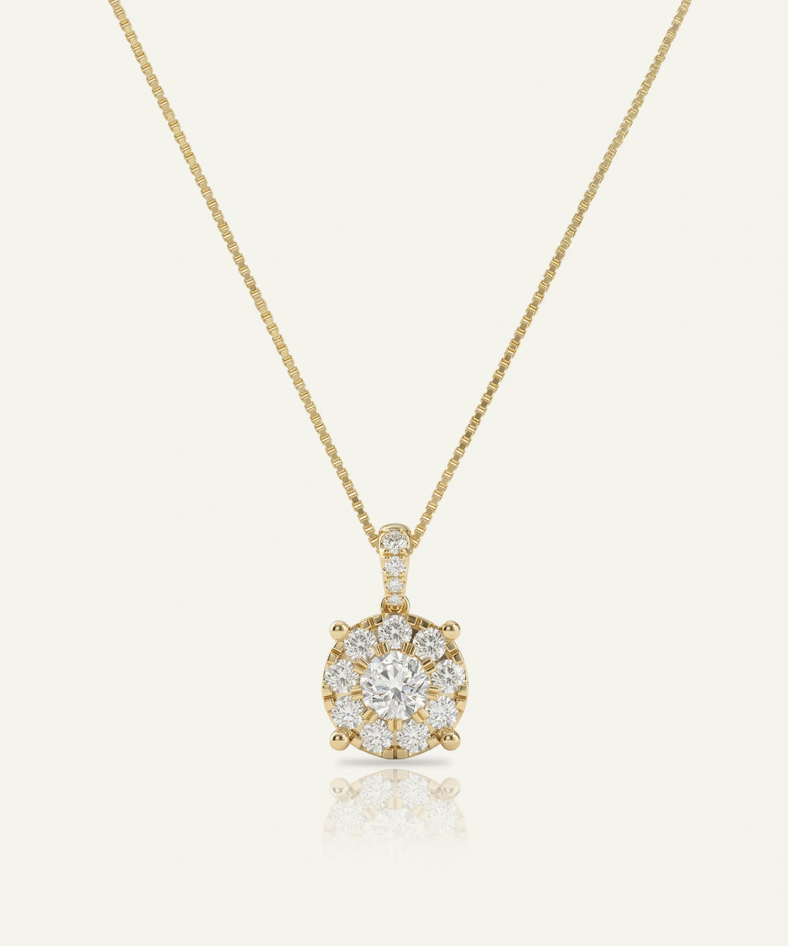 Gold necklace with a diamond pendant on a light beige background