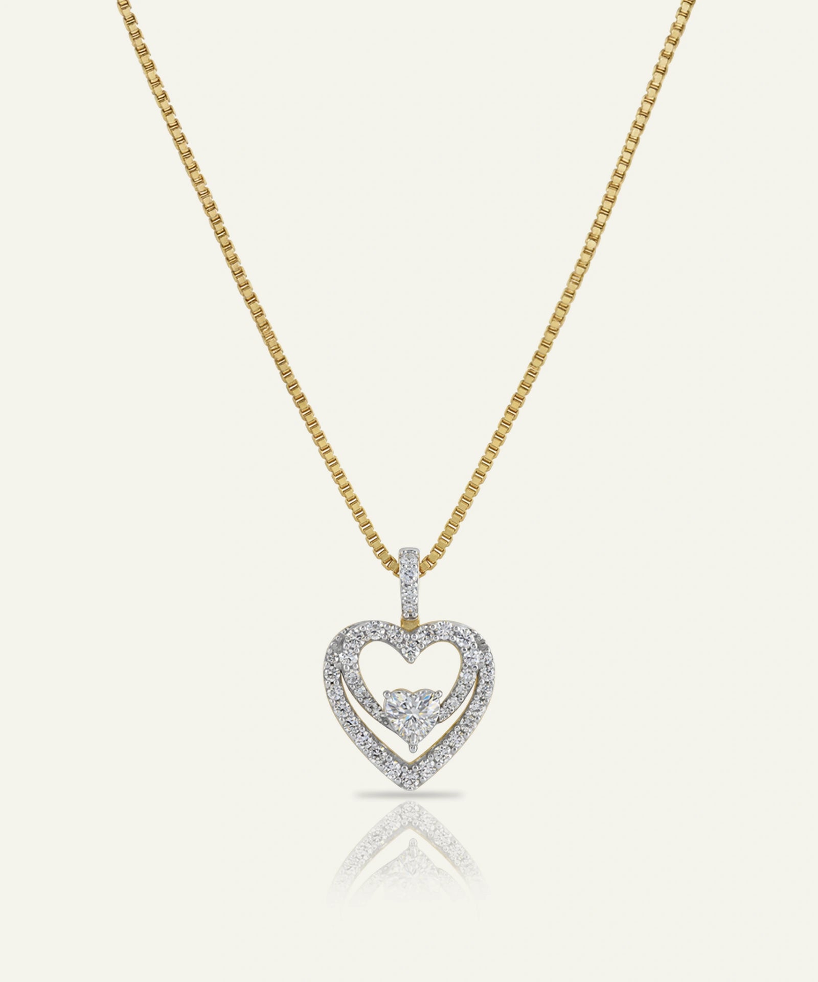 Heart-shaped diamond pendant on a gold chain against a white background
