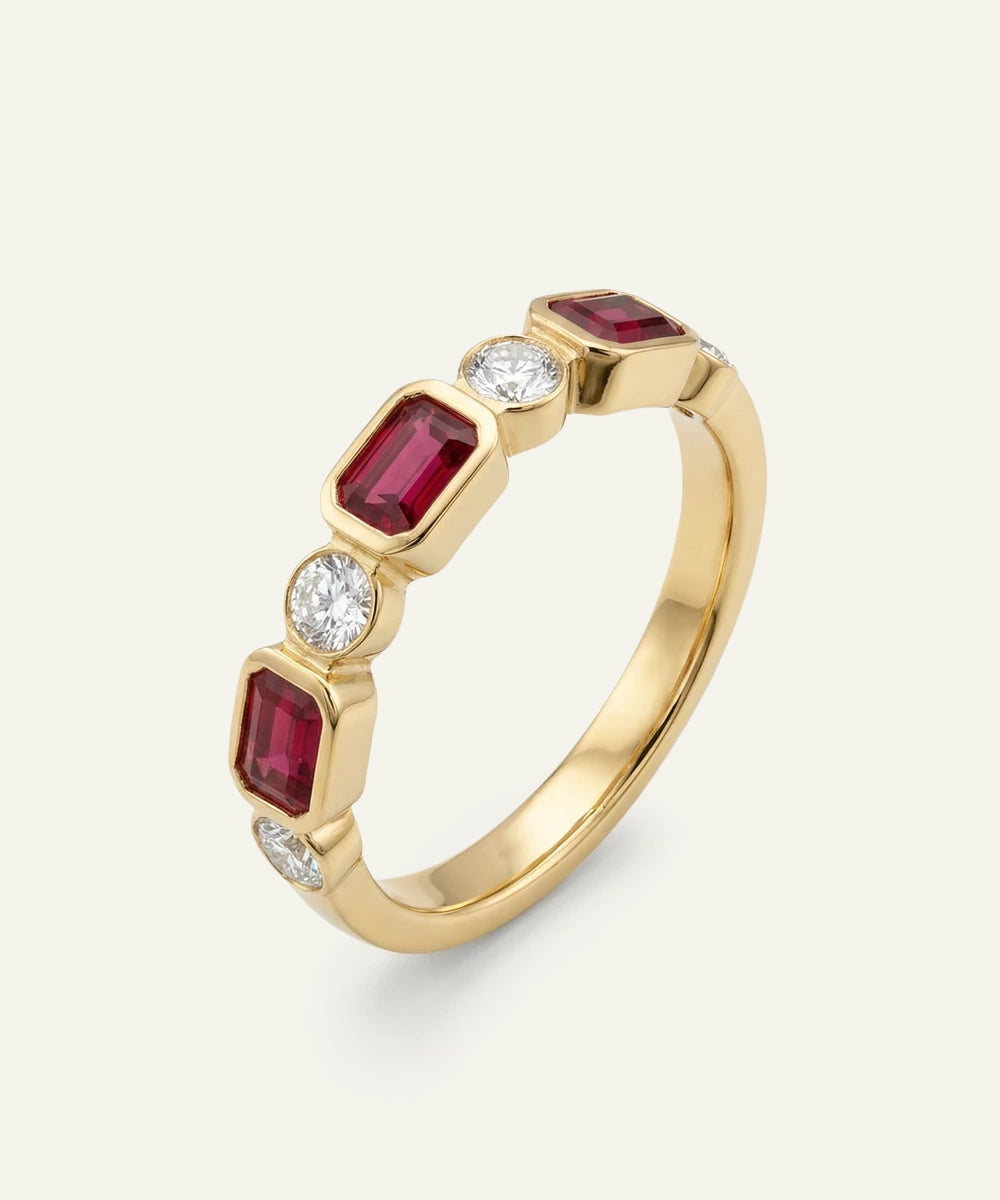 Gold ring with red gemstones and clear stones on a light gray background