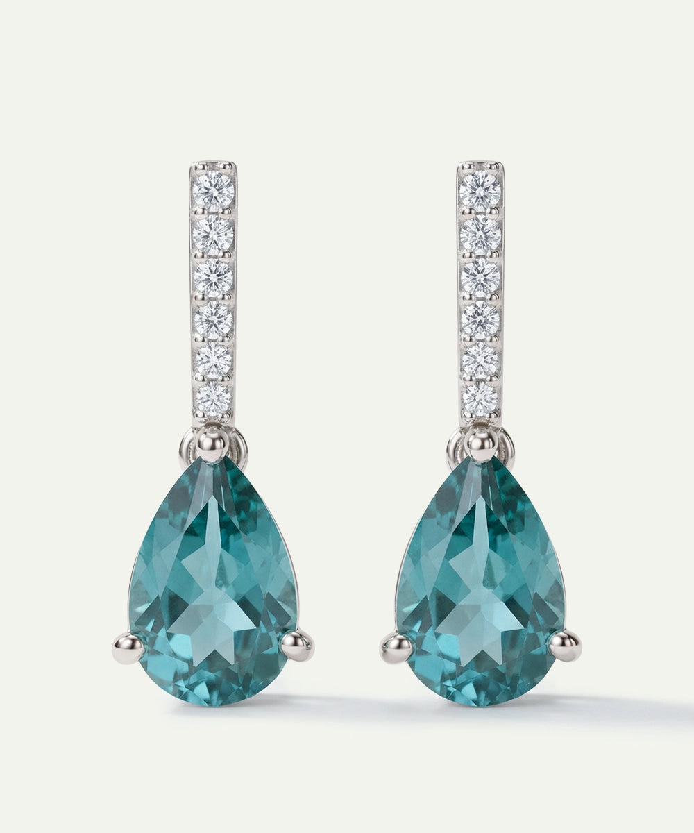 Teal pear-shaped gemstone earrings with diamond accents on a white background