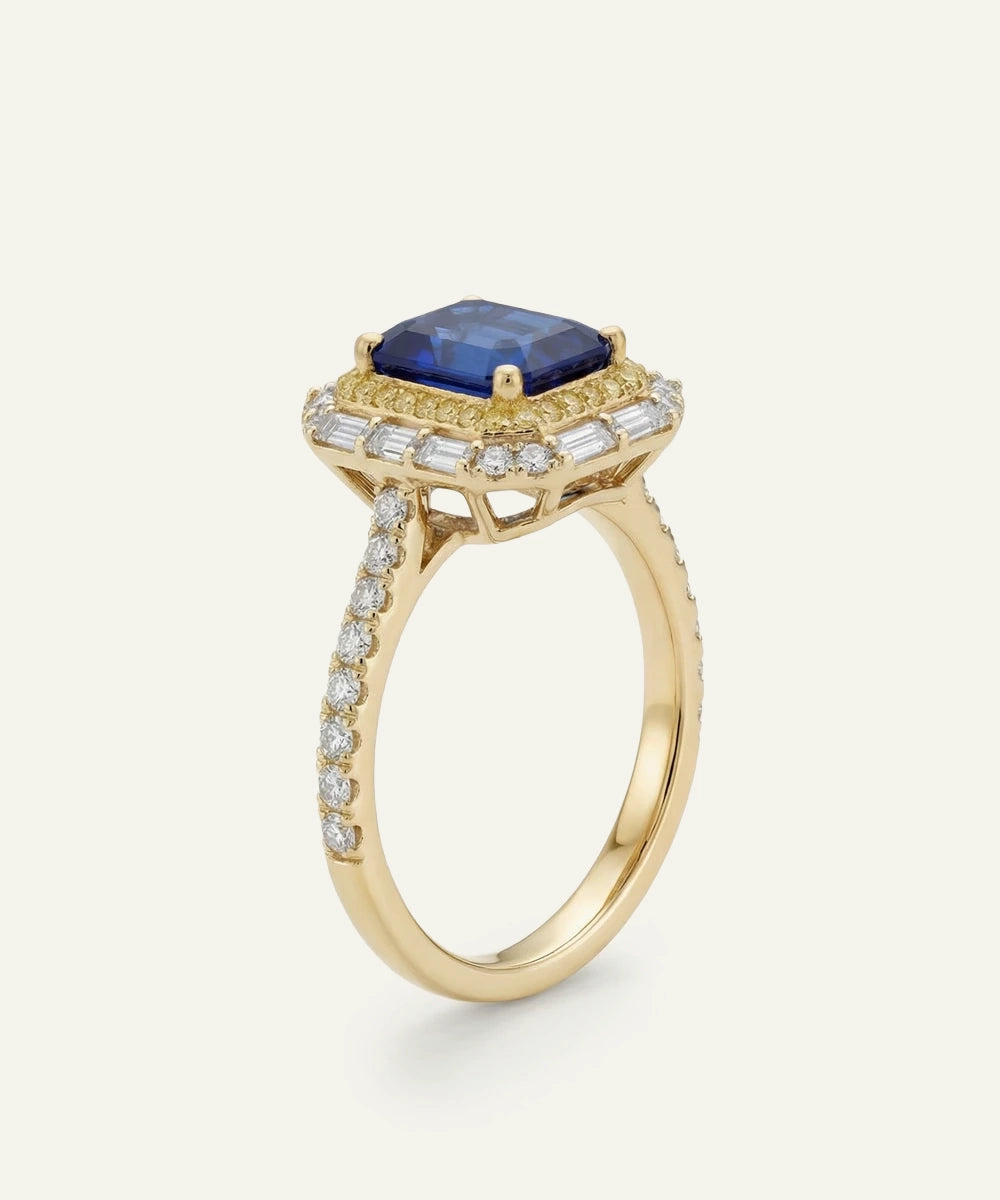 Gold ring with a blue gemstone and diamond accents on a white background