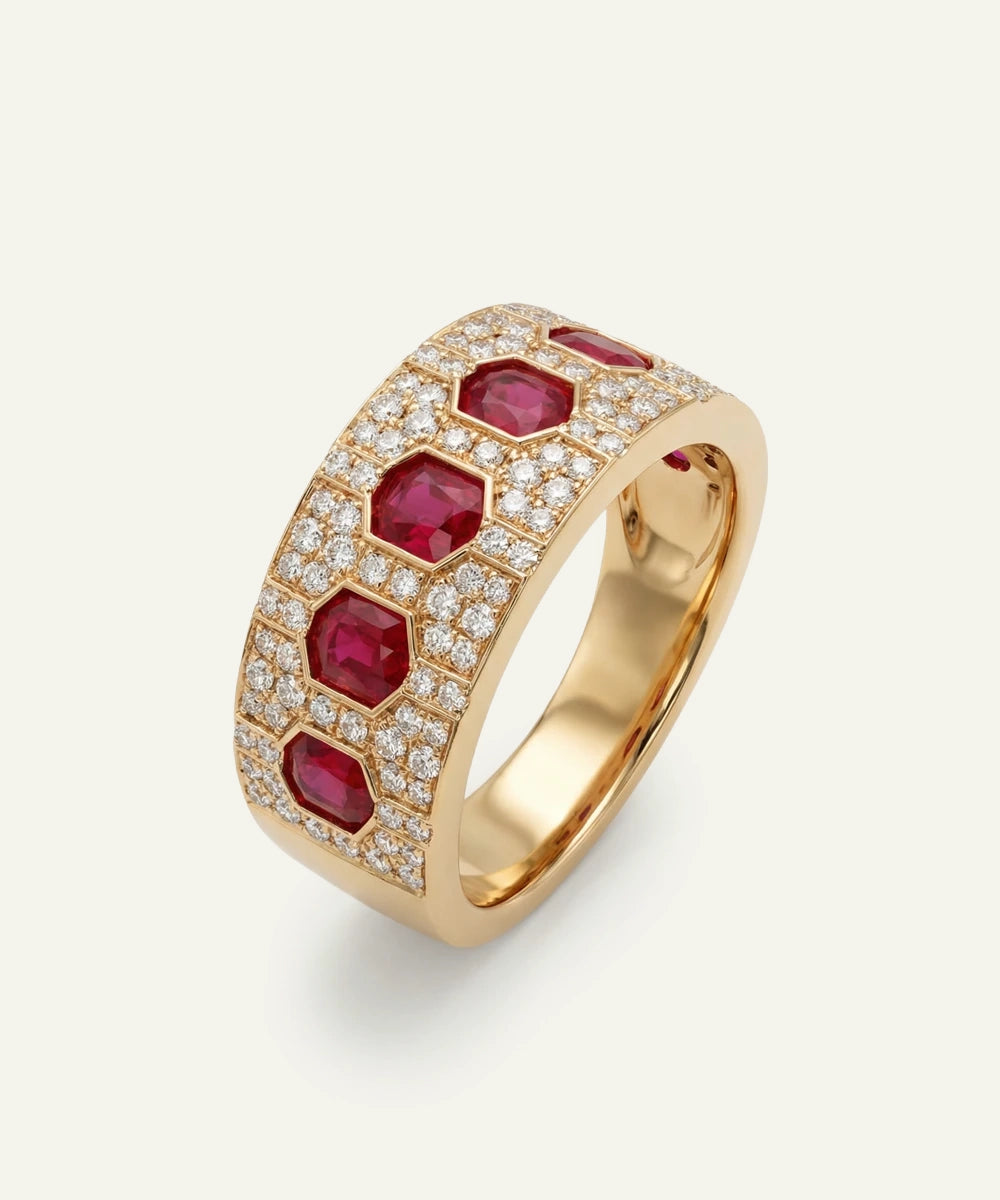 Gold ring with red gemstones and diamonds on a light gray background