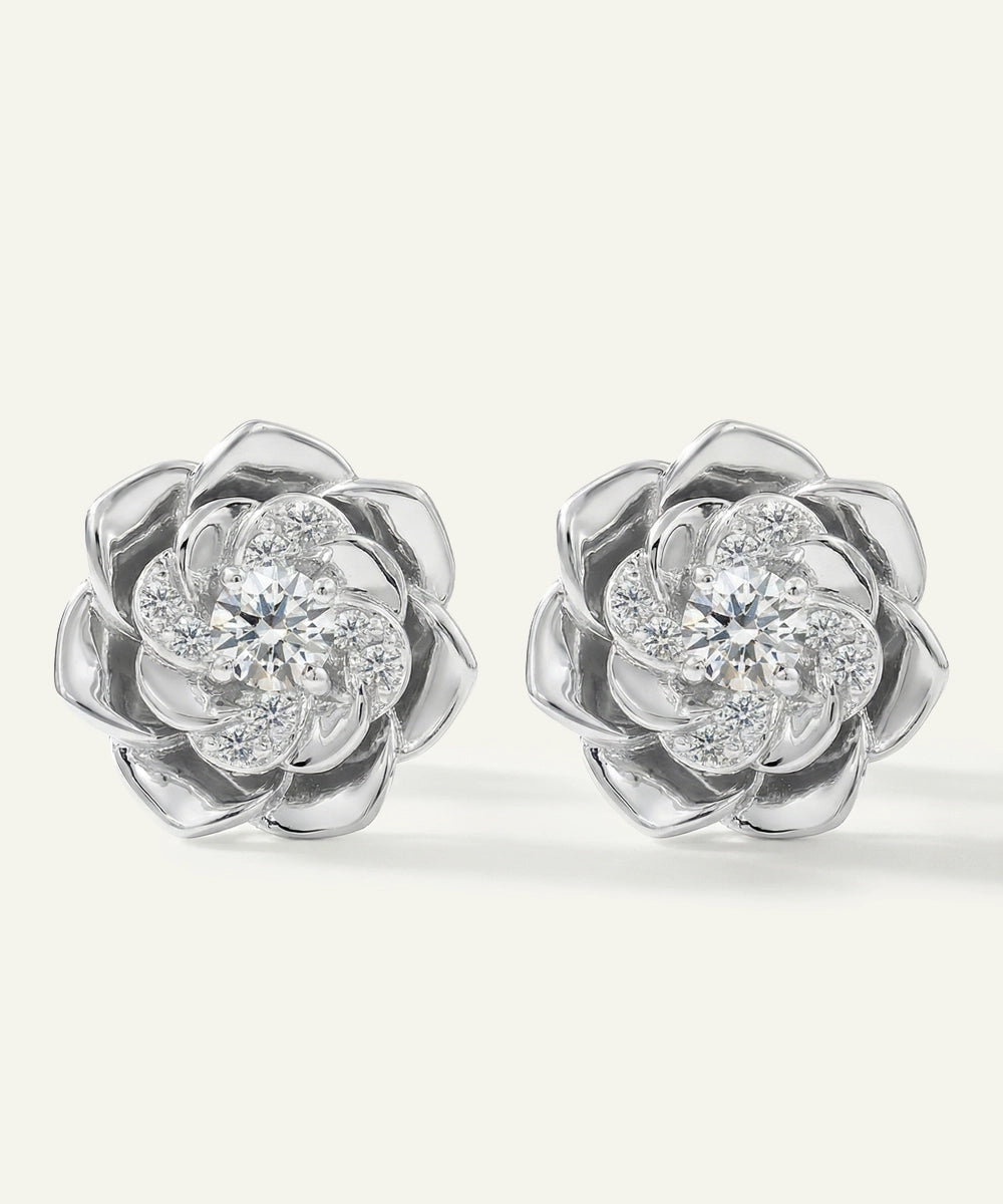 Pair of silver flower-shaped earrings with clear gemstones on a white background