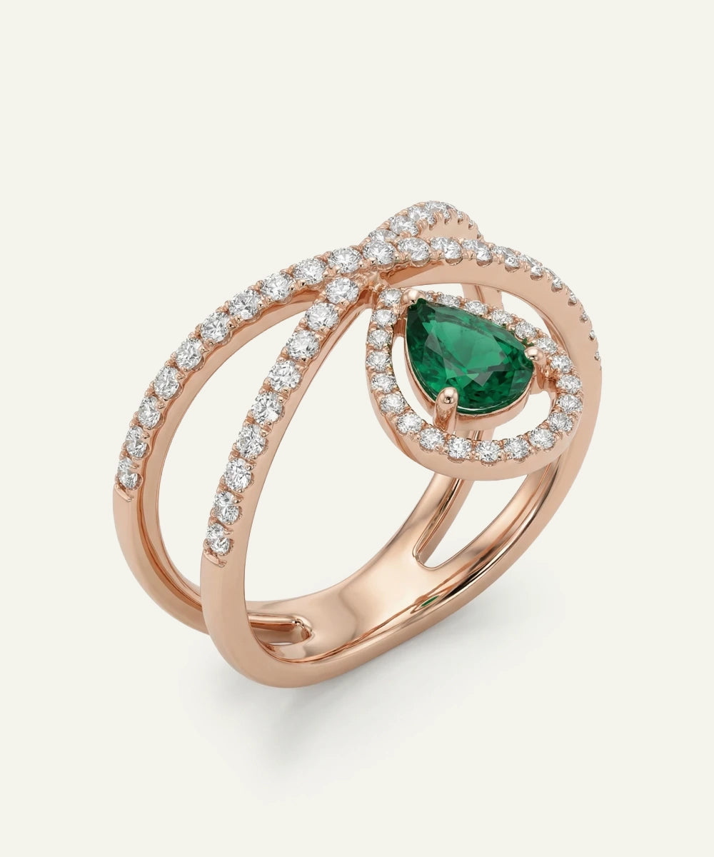 Rose gold ring with emerald and diamonds on a white background