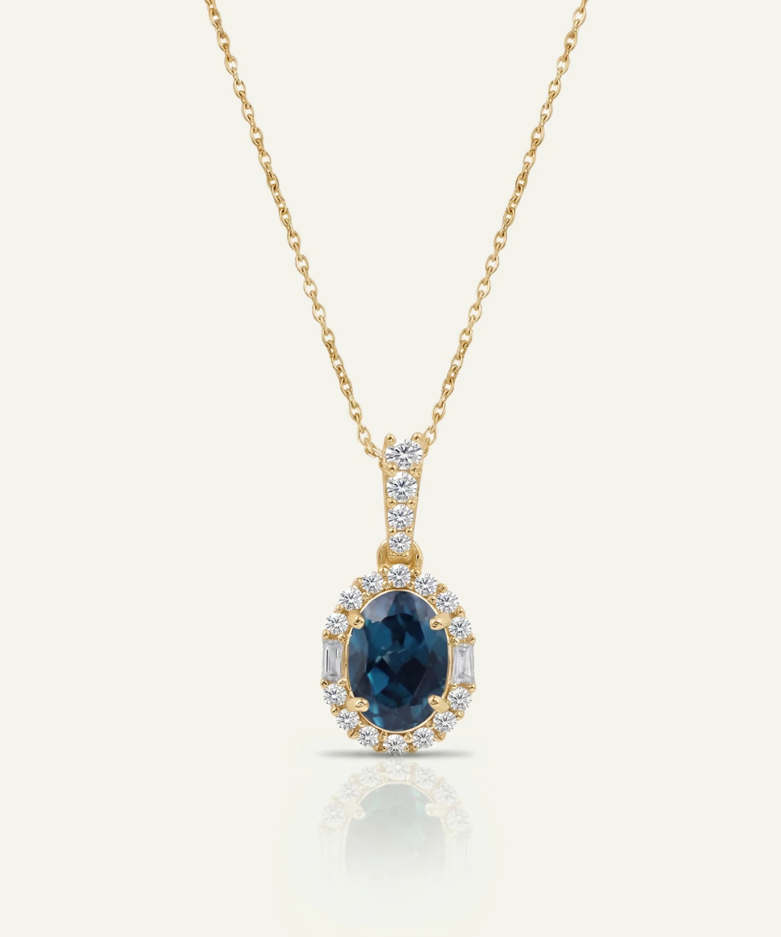 Gold necklace with a blue gemstone pendant on a white background