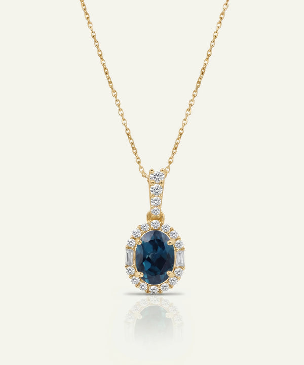 Gold necklace with a blue gemstone pendant on a white background